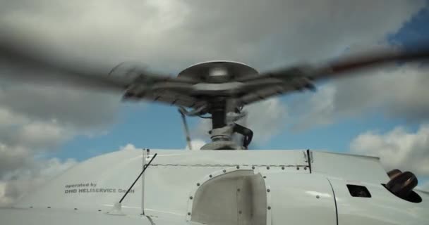 直升机着陆后旋转主旋翼的特写镜头 发动机盖 屋顶和旋翼与天空中的云彩相抗衡 机场和航空概念 — 图库视频影像