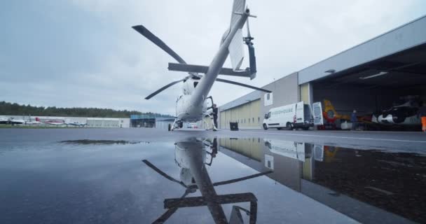 向前移动 在机库前面的浅水坑之上 直升机的低角度后视镜 水面的镜像反射 机场和航空概念 — 图库视频影像