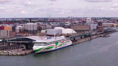 Şehir limanındaki lojistik terminalin kaydırak ve pan görüntüsü. Araçlar feribota yüklenmeyi bekliyor. Arka planda şehir manzarası. Helsinki, Finlandiya.