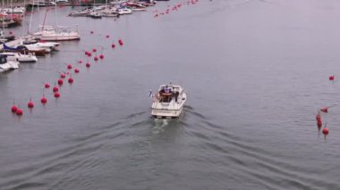 Fin bayrağının limandan geçtiği motorlu tekne manzarası. Su yüzeyindeki kırmızı şamandıralar. Helsinki, Finlandiya.