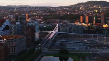 Çok katlı binaları ve geleceksel tasarım yol köprüsü olan modern şehir manzarası. Gün batımında şehir manzarası. Oslo, Norveç.