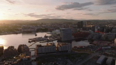 Günbatımında şehrin körfezindeki modern şehir gelişiminin hava görüntüsü. Çok katlı apartmanlar, Munch Müzesi ve Oslo Opera Binası. Oslo, Norveç.