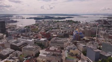 Şehir merkezindeki büyük binaların havadan görünüşü sahile doğru ilerliyor. Adaları ve adaları olan körfezin panoramik manzarası. Oslo, Norveç.