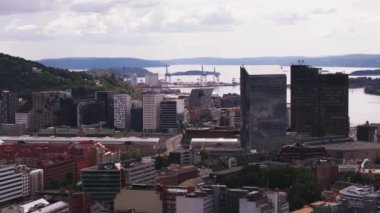 Eski rıhtımlardaki modern yüksek binalar ve otel binaları. Arka planda büyük vinçler var. Oslo, Norveç.