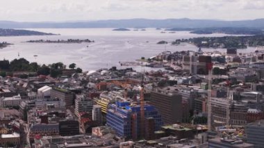 Şehir merkezindeki yeni binaların şantiyesindeki bir grup kule vincinin hava görüntüsü. Geniş körfezde sahil ve su. Oslo, Norveç.