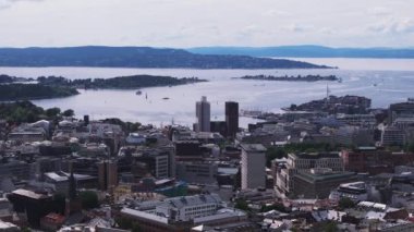 Sahildeki şehir merkezinin hava panoramik manzarası. Belediye binasının işlevsel binası. Su yüzeyinde hareket eden tekneler. Oslo, Norveç.