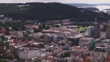 Şehir merkezindeki binaların havadan görünüşü. Tren şantiyeden geçiyor. Şehrin yukarısındaki tepedeki mezarlık ve sahildeki liman. Oslo, Norveç.