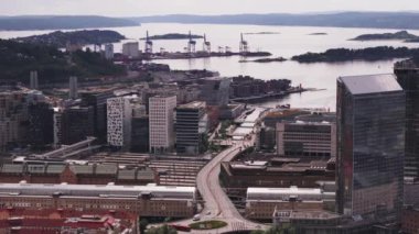 Tren istasyonunun etrafındaki çok katlı binaların hava görüntüleri. Arka planda liman ve büyük vinçler var. Oslo, Norveç.