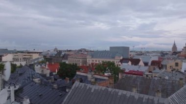 Alacakaranlıkta şehir merkezindeki çatıların üzerinde alçak uçuş. Meydanda yürüyen insanları açığa çıkarmak. Riga, Letonya.