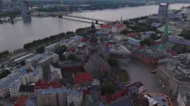 Riga Katedrali 'nin hava görüntüleri, eski kasabadaki meydanı ve evleri çevreleyen. Modern tasarım köprüsü ve Daugava nehrinin arkasındaki yüksek binalar. Riga, Letonya.