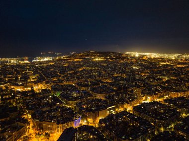 Geceleri şehir merkezindeki geleneksel yapı taşları. Aydınlanmış metropolün havadan panoramik görüntüsü. Barselona, İspanya.