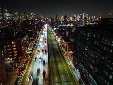 Hareket, metropoldeki kalabalık çoklu şeritli otoyolda trafiğin görüntüsünü bulanıklaştırdı. Arka planda şehir merkezindeki gökdelenler. New York City, ABD.