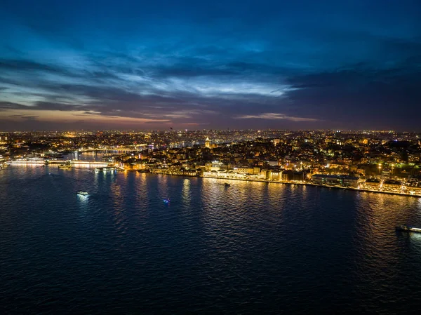 街の照らされた通りや建物の驚くべき夜のショット 水面に浮かぶボート メトロポリスでの夜の生活 イスタンブール トルコ ロイヤリティフリーのストック写真
