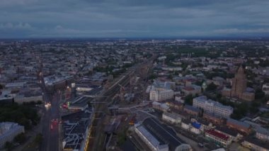 Gün batımından sonra tren istasyonu ve çevresindeki şehirlerin havadan görüntüsü. Yeni binaların inşaat alanındaki vinçler. Riga, Letonya.