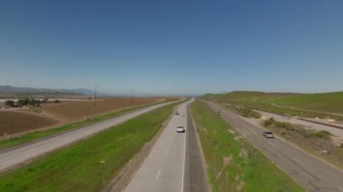İleriye doğru, kırsal alanda birden fazla yol ve demiryolu üzerinde uçar. Taşımacılık altyapısında çalışan araçlar. Kaliforniya, ABD.