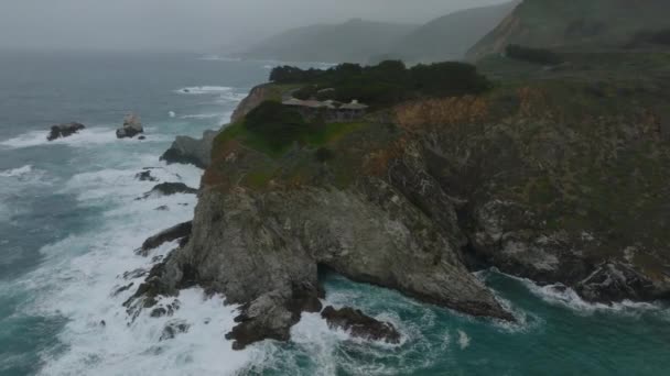 エアリアルスライドとパンショットの波がロッキーアウトクロップに衝突 完璧な景色を望む海岸の家 カリフォルニア アメリカ — ストック動画