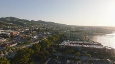 Sabah güneşinde deniz kıyısındaki popüler turizm merkezinin havadan görüntüsü. Yoğun çoklu şeritli otoyol ortaya çıkıyor. Ventura, California, ABD.