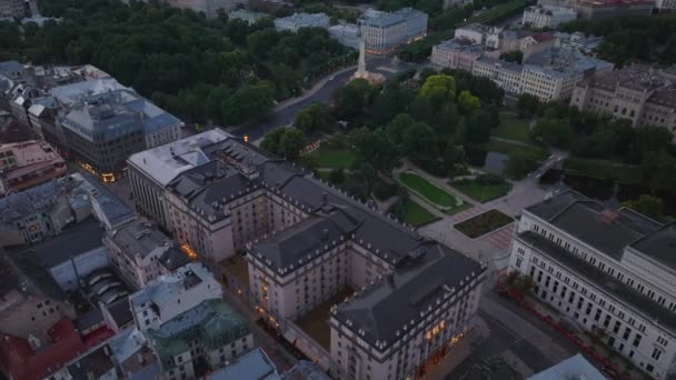 大規模な豪華ホテルの建物と国立オペラの航空写真 日没後の市内中心部の建物や公園の高角度ビュー ラトビア — ストック動画