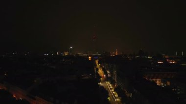 Fırtınada Gece Şehri 'nin havadan görüntüsü. Uzun Fernsehturm TV kulesi silueti aydınlık gökyüzüne karşı görünüyor. Berlin, Almanya