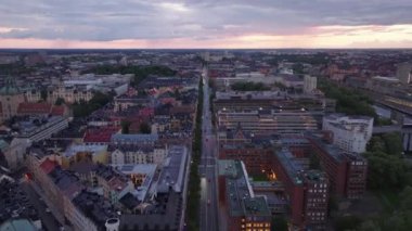 Şehir merkezinden geçen uzun düz bulvarın üzerinde ilerliyorlar. Hava karardığında şehrin panoramik manzarası. Stockholm, İsveç.