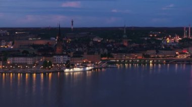 Tarihi şehir merkezindeki Riddarholmen adasına demirlemiş aydınlanmış teknenin hava görüntüsü. Rıhtım ve turistik alanların akşam görüntüleri. Stockholm, İsveç.