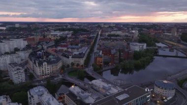 Alacakaranlıktaki liman ve şehir manzarası. Uzun düz cadde boyunca apartman blokları. Stockholm, İsveç.