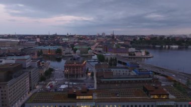 İlerideki liman binalarının üzerinden uçuyor. Gün batımında tarihi şehir merkezinde hava manzarası. Stockholm, İsveç.