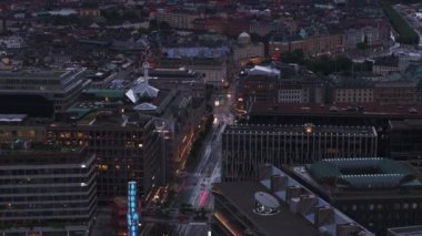 Alacakaranlıkta şehir merkezindeki çok katlı binaların hava sineması görüntüleri. Ticari binalar. Stockholm, İsveç.