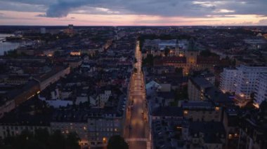 İleriye doğru alacakaranlıkta şehrin üzerinde uçun. Şehirdeki yerleşim yerlerinde sokaklar ve apartman blokları. Stockholm, İsveç.