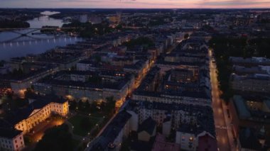 Şehir merkezindeki geleneksel apartman binalarının yüksek açılı manzarası. Günbatımından sonra aydınlık sokaklar ve aydınlık pencereler. Stockholm, İsveç.