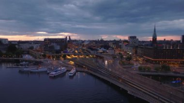 Rıhtımın hava görüntüleri, işlek caddeler ve alacakaranlıktaki ana tren istasyonu. Stockholm, İsveç.