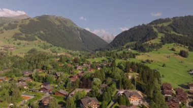 İnanılmaz bir dağ manzarası. İleri, geleneksel dağ tebeşirlerinin ve arka plandaki yüksek dağ sırtlarının üzerinde uçar. Gstaad, İsviçre.