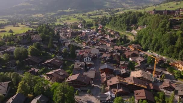 黄金の時間に小さなアルプスの町の通りや建物の空中ビュー 丘の風景の典型的な家やシャレー Gstaad スイス — ストック動画