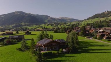Resimli dağ köyünün havadan görünüşü. Alp arazisindeki tipik binalar. Yeşil çimlerle çevrili evler. Gstaad, İsviçre.