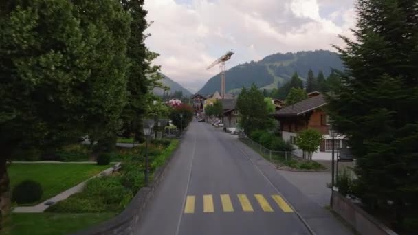 小さな山の町の通りの上を飛行する 高山に囲まれた観光地 Gstaad スイス — ストック動画