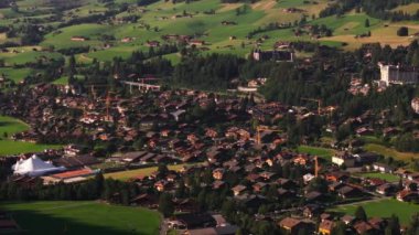 Tipik ev ve kiraz ağaçlarıyla dağlık bir kasabada hava manzarası. Dağ turistlerinin gideceği yer. Gstaad, İsviçre.