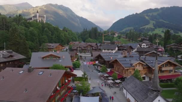 アルペン渓谷の豪華な観光地のエアリアルビュー 山々に囲まれた小さな町の美しい家やシャレー Gstaad スイス — ストック動画