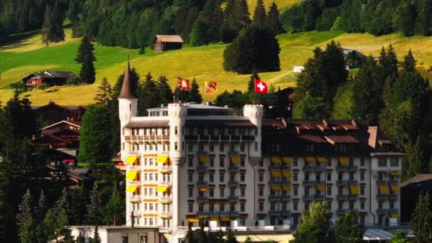 바람에 흔들리는 포탑과 깃발이있는 건물의 확대보기 배경에 초원입니다 Gstaad 스위스 — 비디오