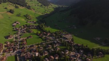 Küçük dağ köyünün yüksek açılı manzarası. Eğim, yüksek dağlar ve yeşil vadiyle panoramik dağ manzarasını gözler önüne seriyor. Gstaad, İsviçre.