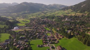 Geniş ve yeşil vadideki tipik bir dağ kasabasının güzel hava manzarası. Altın saatte panoramik dağ manzarası. Gstaad, İsviçre.