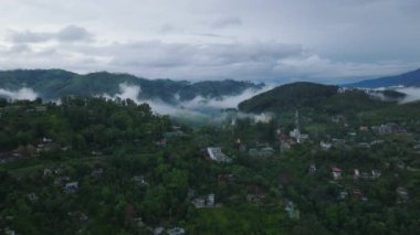 Dağlık arazideki küçük kırsal kasabanın üzerinde uç. Yeşil bitki örtüsünün havadan görünüşü, yağmur ormanları ve vadilerdeki sis. Ella, Sri Lanka.