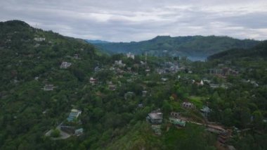 Tropikal ormanlarla çevrili küçük kasabalardaki binaların üzerinden ileriye doğru uçarlar. Yeşil ağaçlar ve bitki örtüsü. Ella, Sri Lanka.