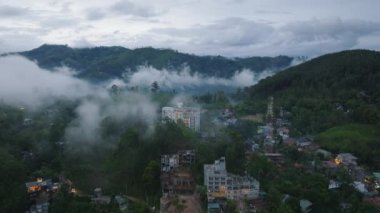 Kasabadaki tropikal ormanlarla çevrili binaların hava görüntüleri. Bereketli yeşil bitki örtüsü, alçak bulutlar ve mistik atmosfer. Ella, Sri Lanka.