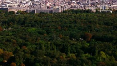 Bois de Boulogne 'daki yeşil ağaçların yüksek açılı görüntüsü. Eiffel Kulesi 'ne hakim olan şehir manzarasını yukarı doğru eğ. Paris, Fransa.
