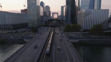Metro trenleri ve arabalar gelecekteki La Defense kentsel bölgesinin altındaki tünele giriyorlar. Günbatımında modern yüksek katlı ofis binaları. Paris, Fransa.
