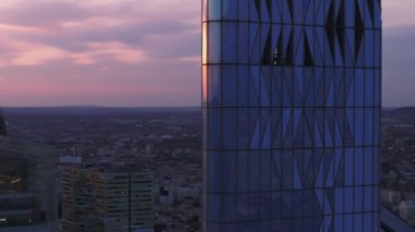 Fütürist gökdelenin en üst kısmının etrafında uç. Günbatımında gökyüzünün romantik rengini yansıtan yüksek binaların cam ön cephesi. Paris, Fransa.