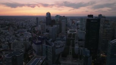 Günbatımında modern iş kentlerinin üzerinde geriye doğru uç. Renkli gökyüzüne karşı gökdelenler. Paris, Fransa.