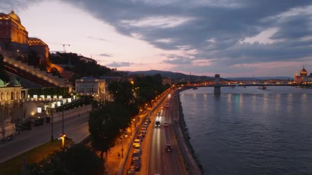 市内の広い川の照らされたウォーターフロントを運転する車 ダヌーブ川沿いの歴史的な都市地区の高架化されたショット ブダペスト ハンガリー — ストック動画