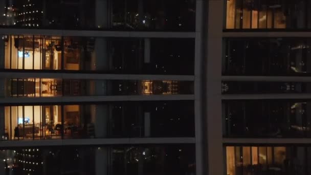 アセンディングは夜に高層マンションに沿って飛ぶ 明るい窓のある人たち 抽象的なコンピュータ効果デジタル構成された映像 — ストック動画