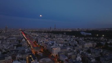 Şehir manzarası, akşamları kalabalık bulvar boyunca binalar. Eyfel Kulesi ve uzaktaki diğer ünlü simgeler. Paris, Fransa.
